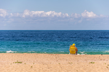 Tourist on the beach sitted on his yellow chair