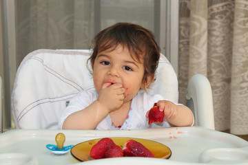 One year old baby boy eating strawberryes