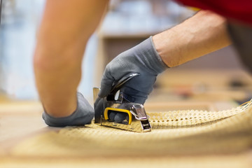 production, manufacture and industry concept - assembler with staple gun making furniture