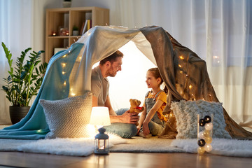 family, hygge and people concept - happy father with teddy bear toy and little daughter playing in...
