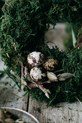 Spring Easter wreath with quail eggs, decoration in the interior and on the head. Compositions of moss and greenery on a wooden background