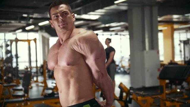 Athletic man with naked muscular torso in workout room
