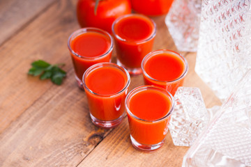 Cold Bloody Mary cocktail shot in glasses and tomatoes 