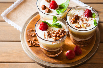 Dessert with berries, jelly, cream, nuts and mint leaf on a cutting wooden board 