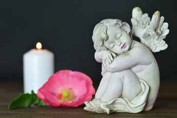Angel, flower and candle on wooden background