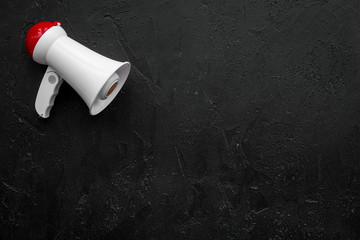 Announcement concept. Megaphone on black background top view copy space