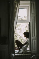 Pretty young black woman sitting on the window