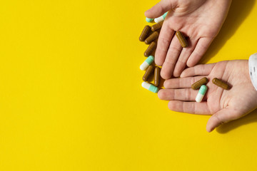Topic pharmaceutics. Colored capsules in the hands of the boy, on a yellow background.