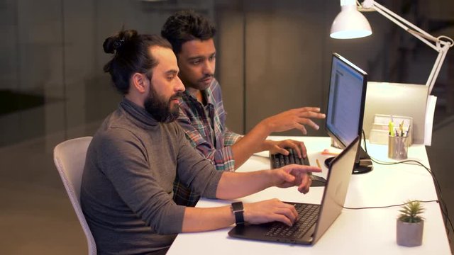 deadline, technology and people concept - programmers with computers working together late at night office