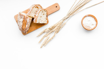 Homemade fresh bread sliced on cutting board on white background top view copy space