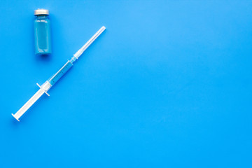 Medical injection. Syringe and bottle with remedy on blue background top view copy space