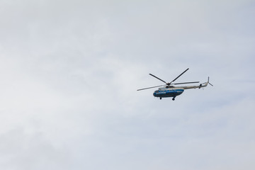 Fototapeta na wymiar Helicopter high flying at the gray sky
