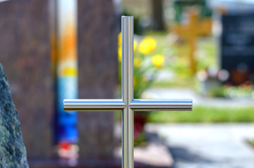 Simple metal cross on a grave in a cemetery