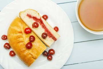 Fresh cooked pie with jam and black tea. Scattered berries. Homemade healthy breakfast on wooden table. Top view