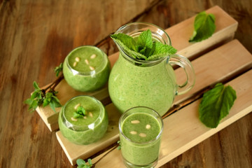 Green smoothie in glass vessels on wooden background