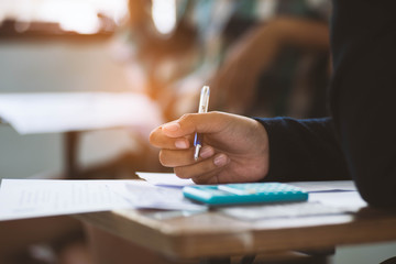 Close up Students writing and reading exam answer sheets exercises in classroom of school with stress.