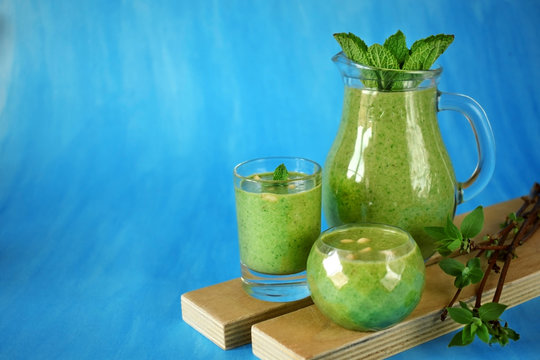 Green smoothie in glass vessels and on blue background. Copy space