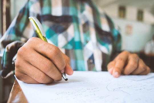 Close up Students writing and reading exam answer sheets exercises in classroom of school with stress.