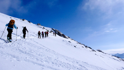 Fototapeta na wymiar a group of backcountry skiers head towards the summit on their backcountry ski tour in the mountains of the Swiss Alps