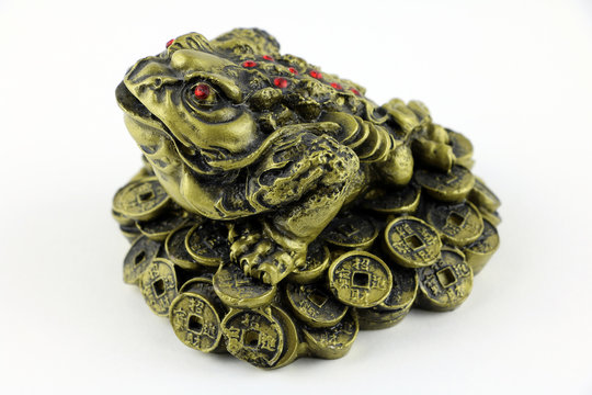 Chinese Feng Shui lucky frog, toad with red eyes, with coins, symbol for abundance, luck and riches. Isolated on white background