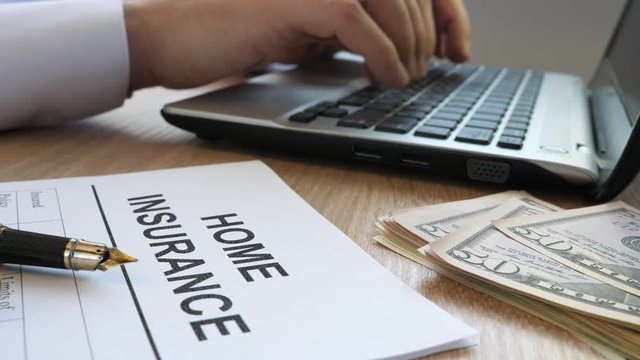 Home insurance form and manager typing on a laptop.