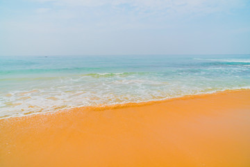 Blue waves of the ocean and yellow sand of the beach.