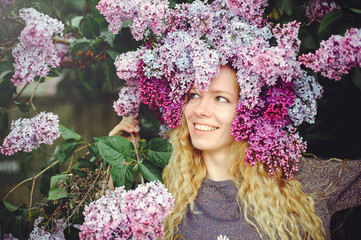 Outdoor fashion photo of a beautiful young blue-eyed woman. Spring color. beautiful blonde girl in lilac flowers. Perfume with a scent of flowers. Perfumes and beauty