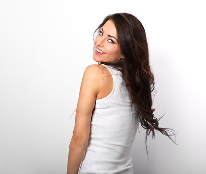 Beautiful positive excited laughing young woman moving the long hair in white shirt and with toothy smile on white background