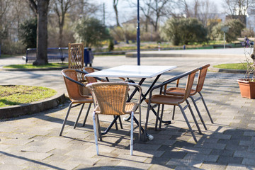 Obraz premium geflochtene Stapel Stühle oder Gartenstühle an einem Tisch im Freien bei sonnigem Wetter