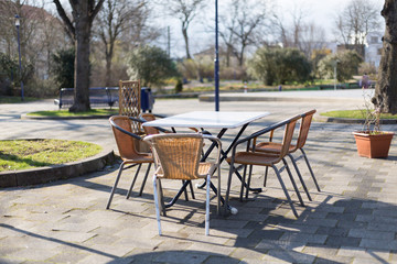 Fototapeta na wymiar geflochtene Stapel Stühle oder Gartenstühle an einem Tisch im Freien bei sonnigem Wetter