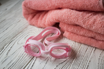 pink swimming goggles and a pink towel on the wooden table