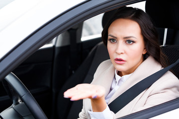 Young pretty woman driver driving a car and arguing with someone