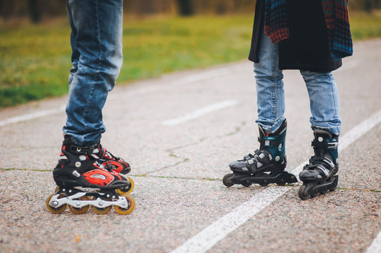 Two pairs of feet on roller skates on the road in the park.