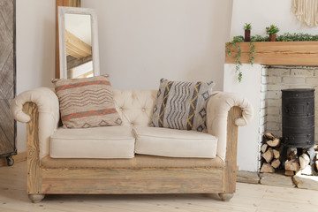Beige sofa with pillows near the fireplace. Interior of the living room. Scandinavian style