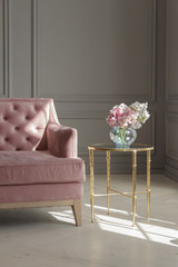 A large beautiful pink sofa stands in a spacious living room in a classic style.