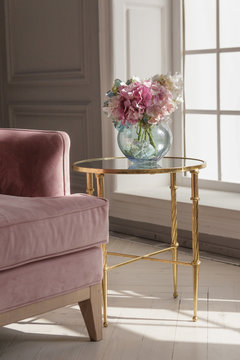 A large beautiful pink sofa stands in a spacious living room in a classic style.