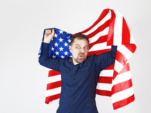 Photo of caucasian man holding bristle holding big american flag looking with embarrassment and surprise isolated over white background