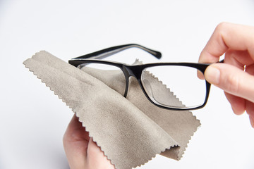 A hand with a napkin wipes glasses on a white background.