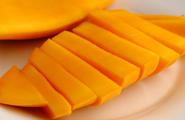 Fototapeta na wymiar Slice ripe juicy sweet Thai mango fruit on a white dish close up and selective focus