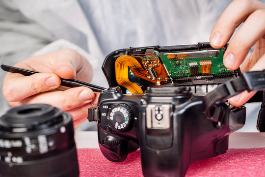 Close up hands of a service worker repairing digital camera.