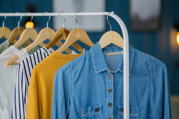 Clothes hang on wooden coat hangers in clothing store with home tone. Shopping and spending concept