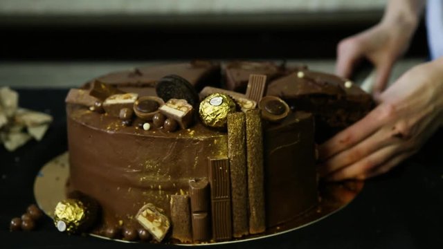 confectioner hands cut by knife big chocolate cake