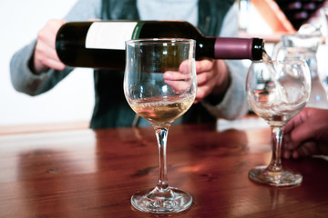 Sommelier of the tasting room of the winery company pouring white wine into a glass