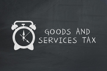 inscription GST and alarm clock drawn on chalkboard