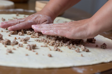 Woman making dough with meat at home