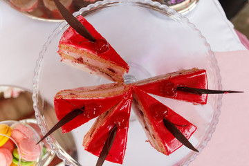 A Pieces of red cherry cake covered with mirror red glaze on a glass tray.