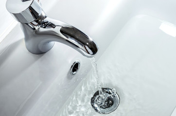 Faucet with a jet of water. A stream of clean water pours from the tap into the sink. Top view..