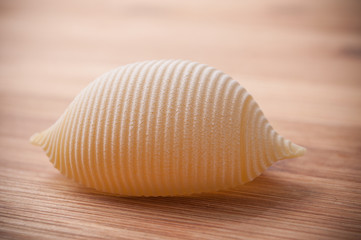 closeup of shaped seashell pasta on wooden cutting board in bamboo texture background