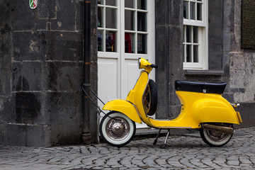 A yellow retro style scooter parked in Essen