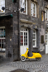 A yellow retro style scooter parked in Essen